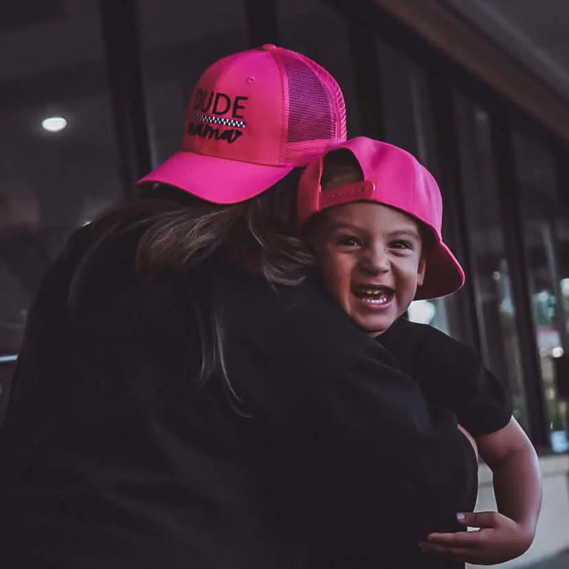 Mama and child wearing hot pink checkered matching hats for family fun and connection.