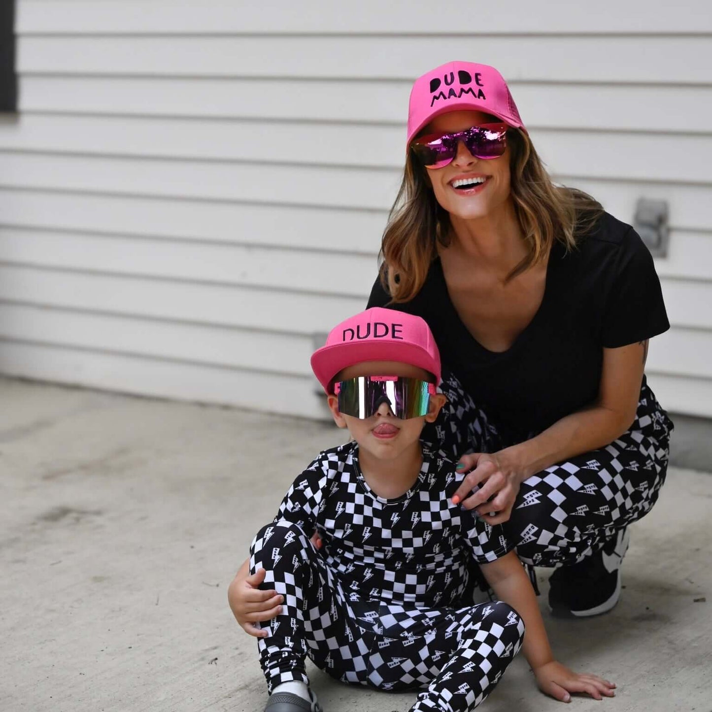 Mom and son matching in stylish checkered pajamas and hats with sunglasses, showcasing a trendy 'Dude Mama' look.
