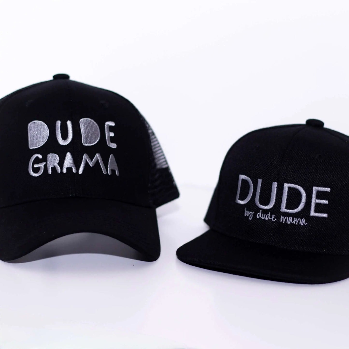 Two black hats showing 'Dude Grama' and 'Dude' text, showcasing the stylish grandma hat design.