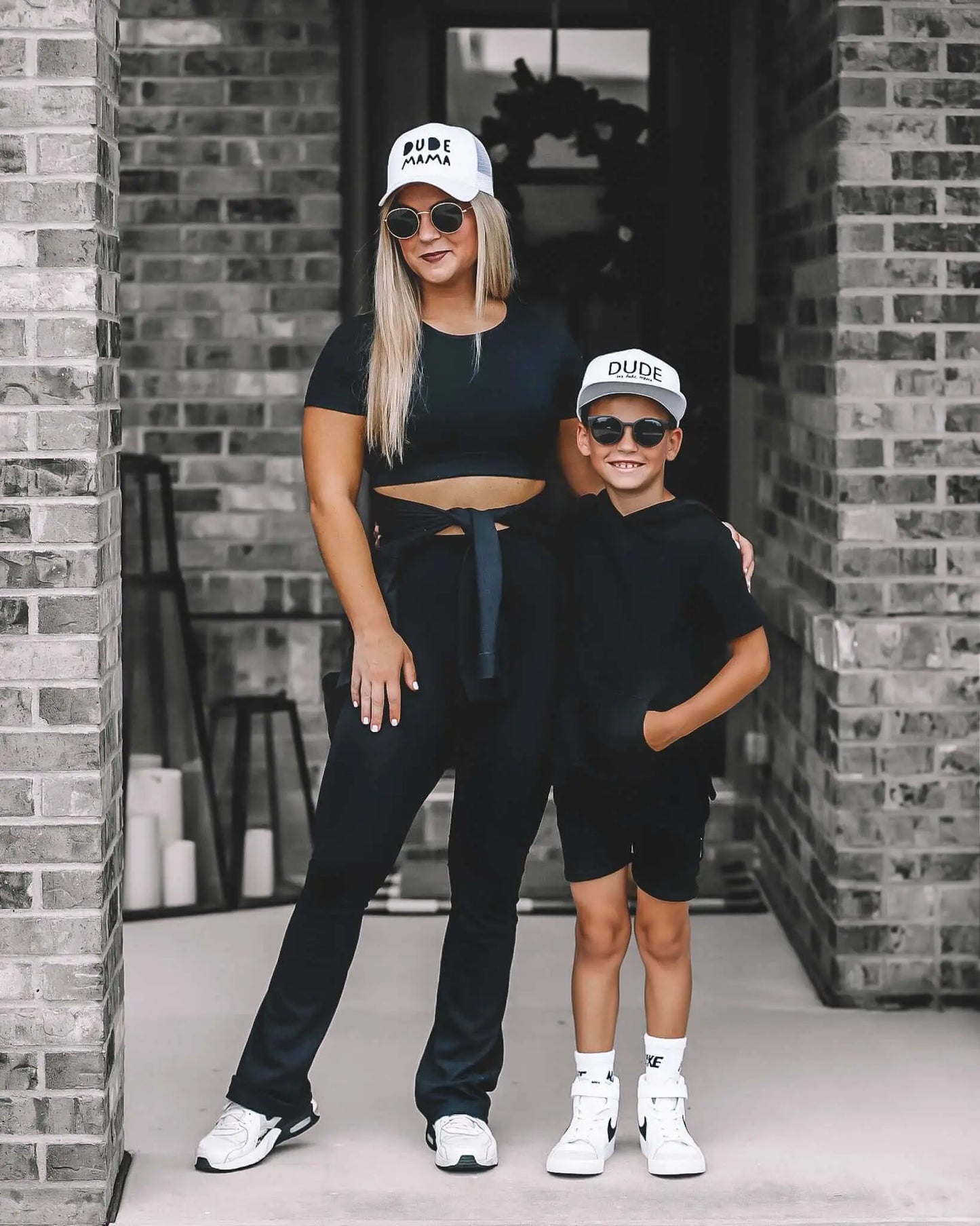 Mother and son wearing black outfits and matching Dude hats, showcasing the stylish Classic White Dude Boy Hat.