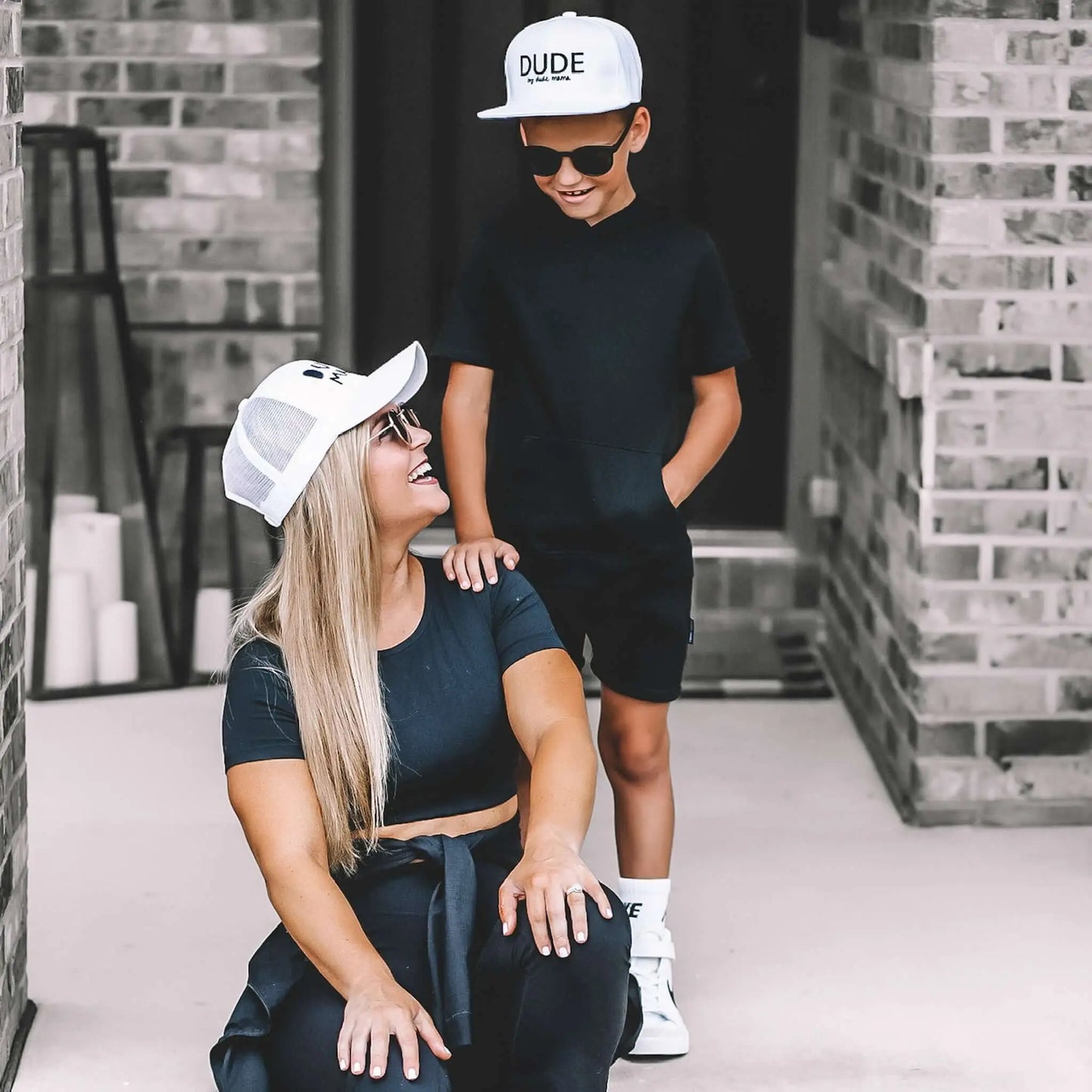 Mom and son wearing matching white hats. They are looking at each other smiling.