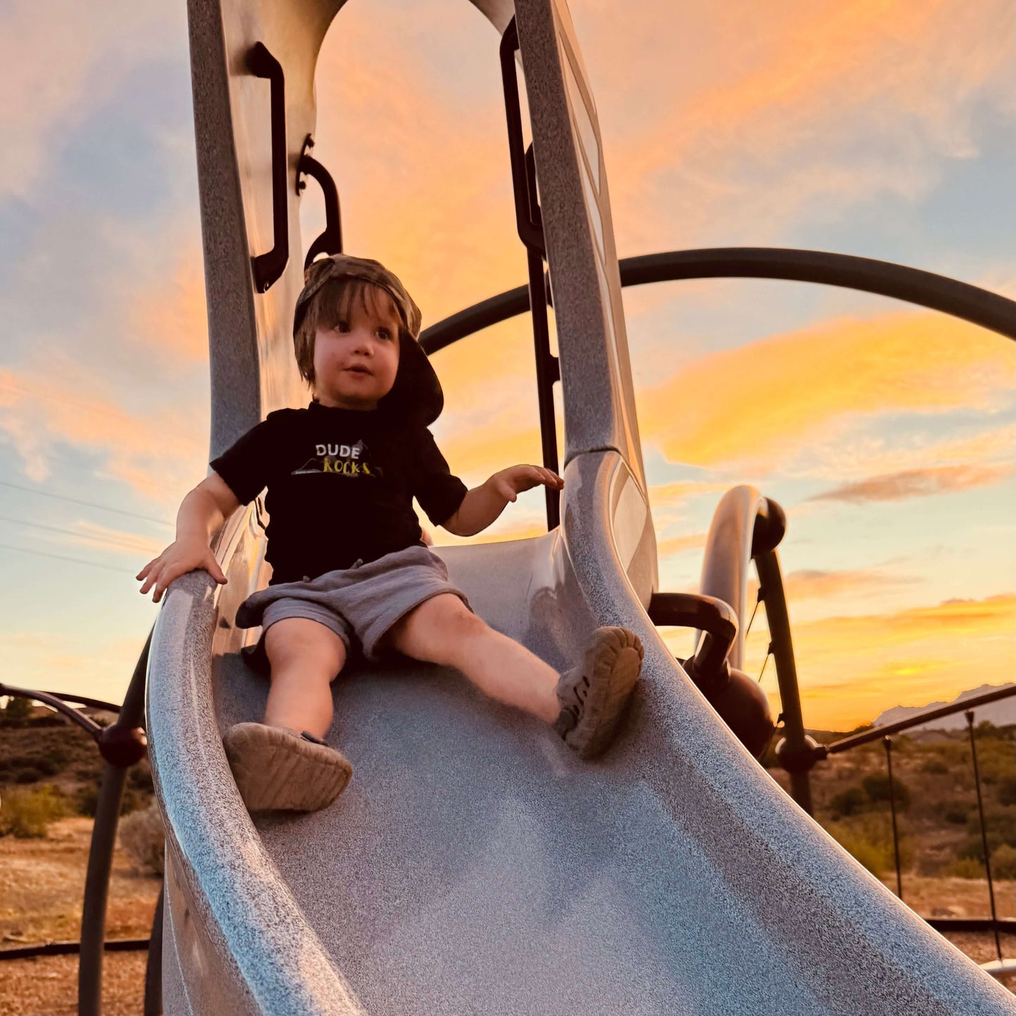 Boy enjoying a slide while wearing a stylish green camo dude boy hat.