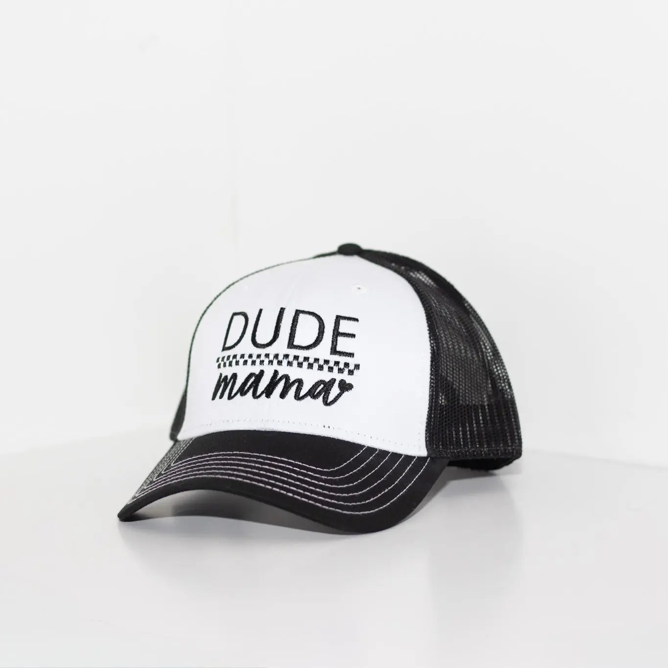 Black and white boy mom hat w/ contrast stitching. The hat says 'Dude Mama' and is on a light gray background. It's a picture at a slight angle.