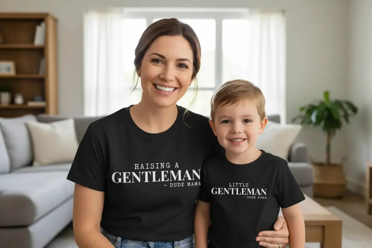 Mom and Son wearing a Mom and Son Matching Outfit. Mama's shirt says 'Raising a Gentleman' and her son's shirt says 'Little Gentleman' - both are black shirts with white font.
