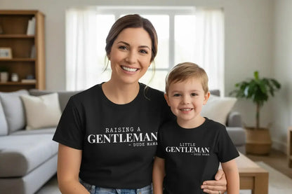 Mom and Son wearing a Mom and Son Matching Outfit. Mama's shirt says 'Raising a Gentleman' and her son's shirt says 'Little Gentleman' - both are black shirts with white font.