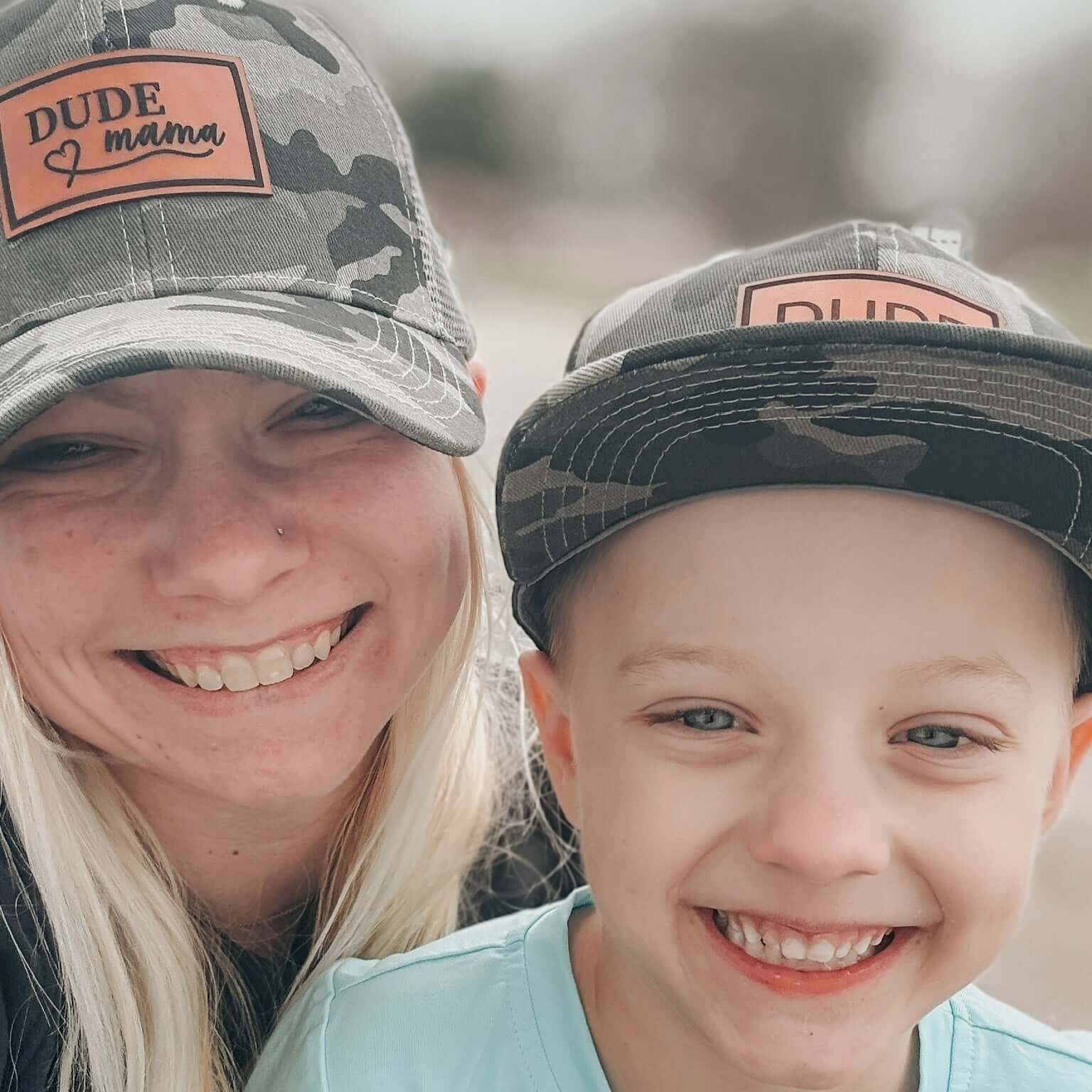 Matching hats for mama and dude with camo print and leather patches, perfect for family activities.