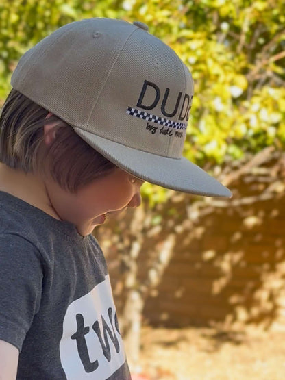 Khaki and checkered dude boy hat worn by a boy, showcasing style and confidence in outdoor setting.
