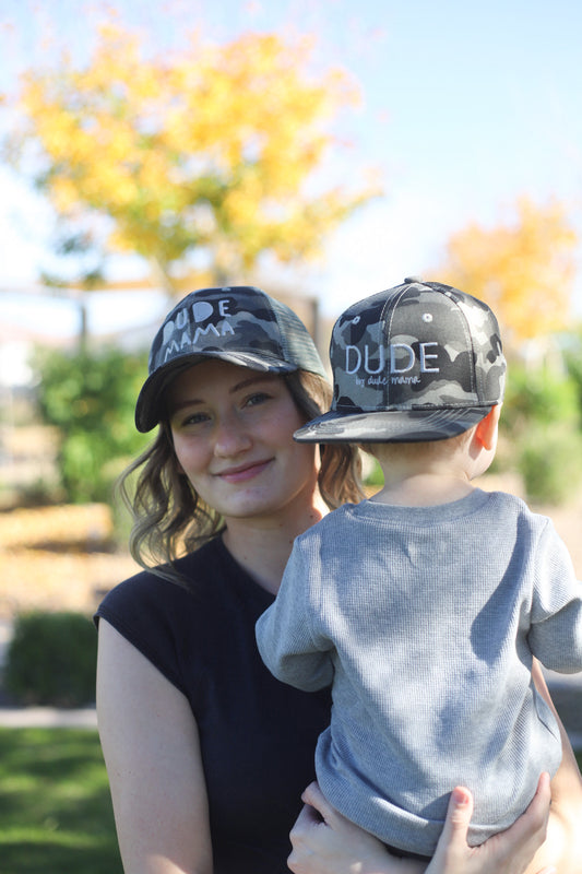 Matching mom and son hats featuring a camouflage design, showcasing a woman and child wearing matching caps outdoors.