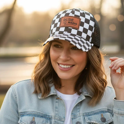 Woman smiling while wearing a Checkered Dude Mama Hat, featuring a stylish black and white design. This is a great boy mom hat.