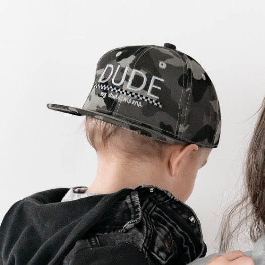 Boy wearing a Camo Checkered Dude Hat, a durable boys hat for casual outings.