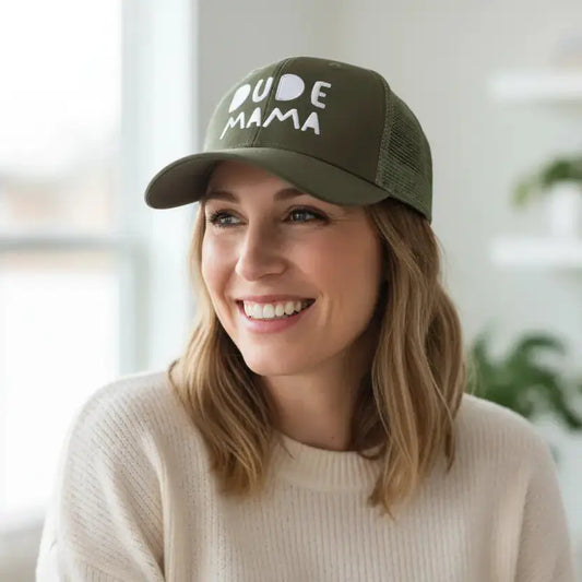 Mom smiling wearing a boy mom hat. It is green with white text that says 'Dude Mama'.