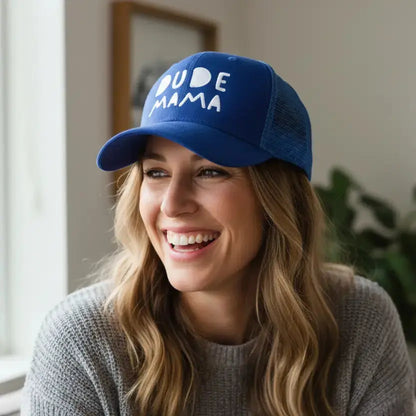 Mom smiling wearing a boy mom hat. It is royal blue with white text that says 'Dude Mama'.
