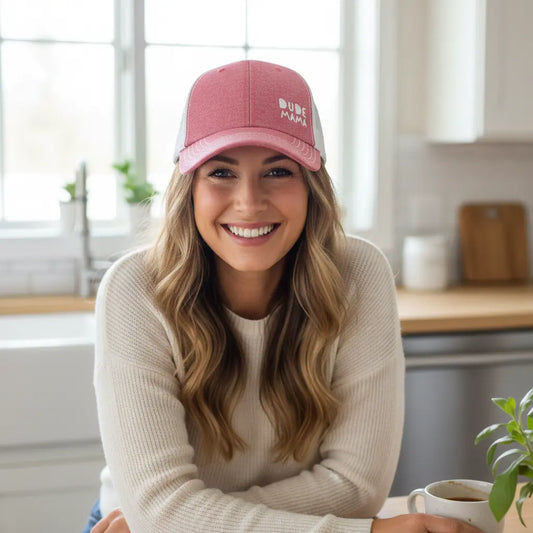 Mom smiling wearing a boy mom hat. It is light red and white and says 'Dude Mama'.