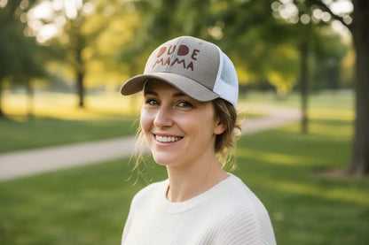 Mom smiling wearing a boy mom hat. It is charcoal and white and says 'Dude Mama'.