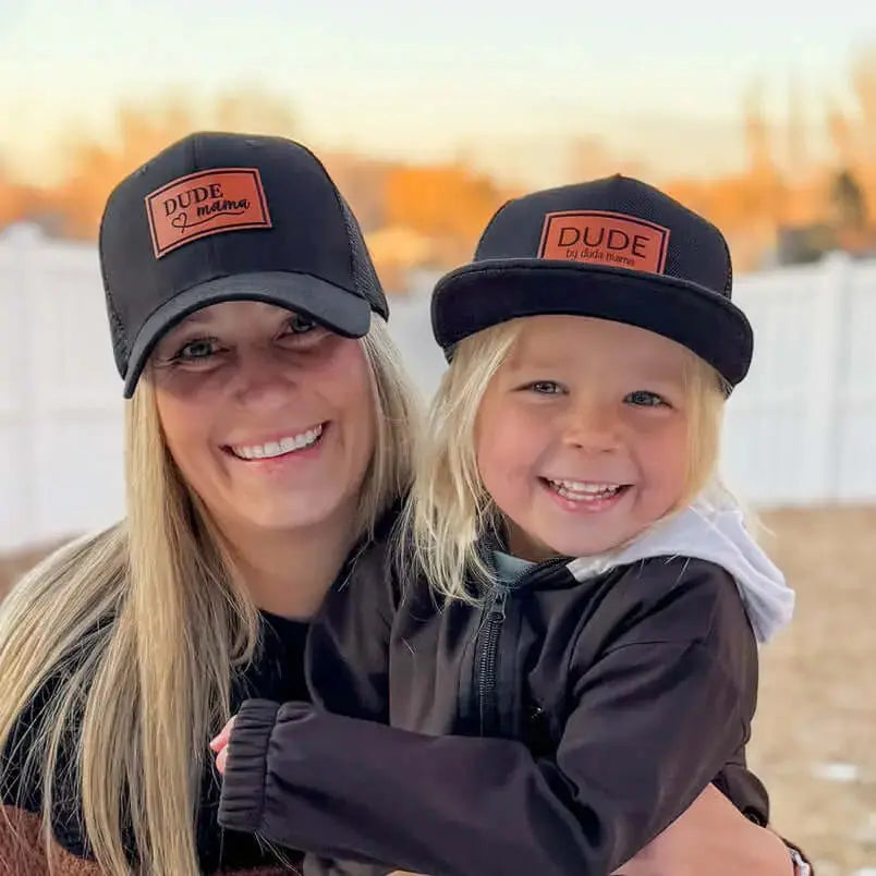 Mama and child wearing matching hats with leather patches, highlighting connection and joy. Boy mom hat and Dude hat
