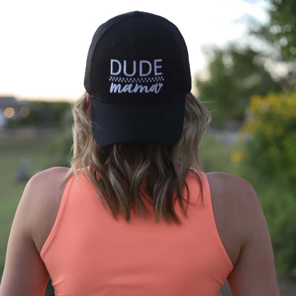 A woman wearing a boy mom hat backwards. The hat is embroidered and says "Dude Mama" with a heart on it. She is outdoors. This is an adorable boy mom hat.