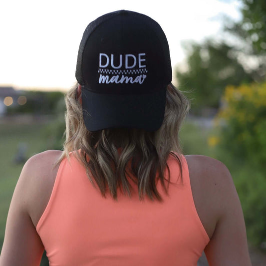 A woman wearing a boy mom hat backwards. The hat is embroidered and says "Dude Mama" with a heart on it. She is outdoors. This is an adorable boy mom hat.