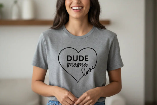 Mom smiling wearing a gray boy mom shirt that says 'Dude Mama' in a heart graphic.